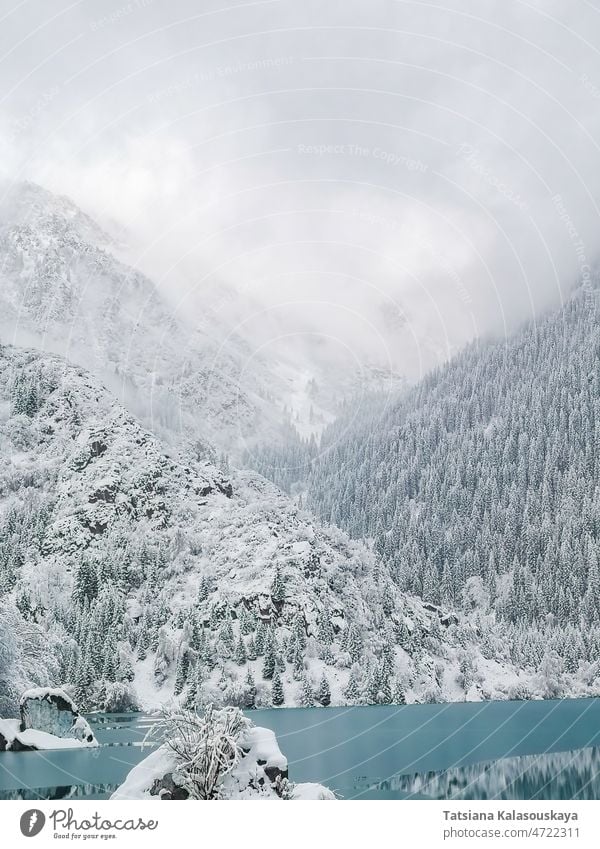eisbedecktes türkisfarbenes Wasser eines Bergsees vor der Kulisse von Bergen in Nebel und Wolken See Wald Eis Schnee Issyk Kasachstan Almaty Mittelasien Norden