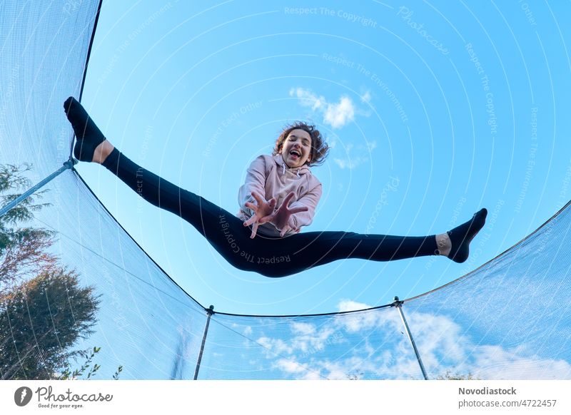 Porträt eines glücklichen 13-jährigen Mädchens, das auf einem Trampolin springt Teenager 13-18 Jahre allein vereinzelt im Freien aktiv hoch springen springend