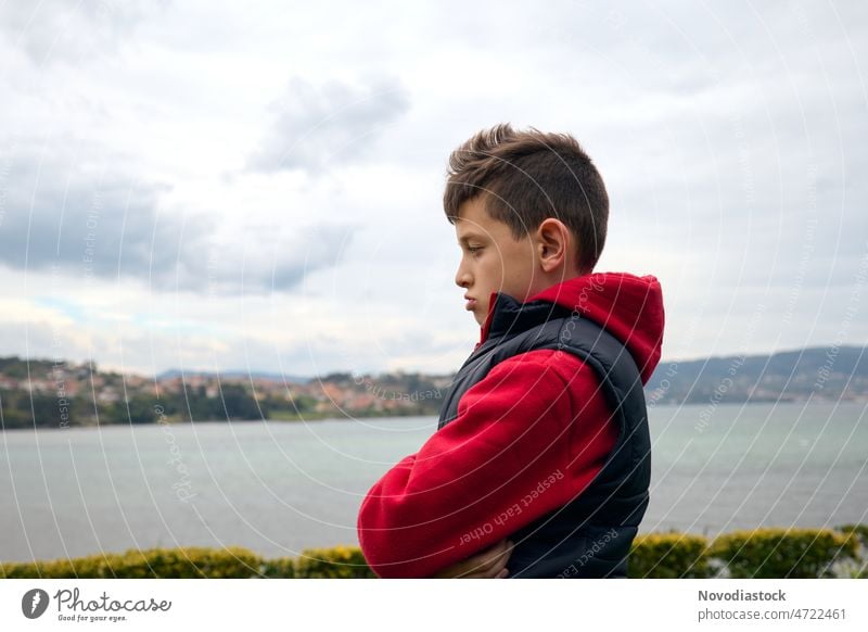 Porträt eines 9-jährigen Jungen im Freien, der wütend und aufgebracht aussieht, Meer im Hintergrund, Profilbild 9 Jahre alt Kind allein isolierter Mensch Person