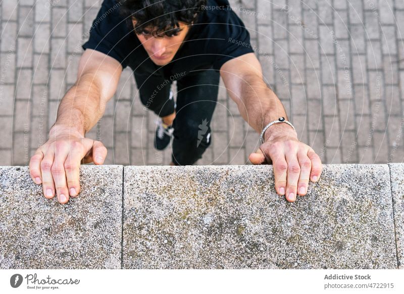 Mann hält Hände an die Wand und hängt Training Straße passen Halt hängen Athlet Händchenhalten Großstadt männlich Typ Le Parkour Übung Fitness Borte Sportler