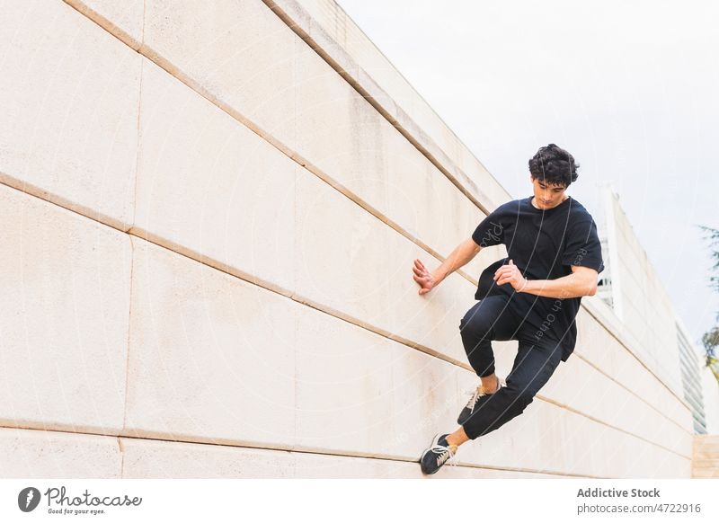 Sportlicher Mann macht Parkour-Stunt an der Wand auf der Straße Le Parkour springen Gebäude über der Erde akrobatisch Energie ausführen Typ männlich Trick