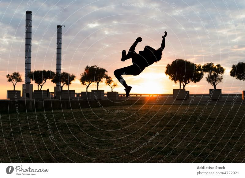 Springende Silhouette einer aktiven Person bei Sonnenuntergang Mann springen Trick Le Parkour über der Erde Freiheit Energie männlich Typ unkenntlich anonym