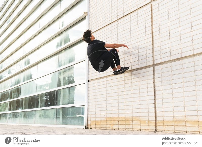 Sportlicher Mann beim Parkour auf der Mauer auf der Straße Le Parkour springen Stunt Gebäude über der Erde akrobatisch Energie ausführen Typ männlich Trick