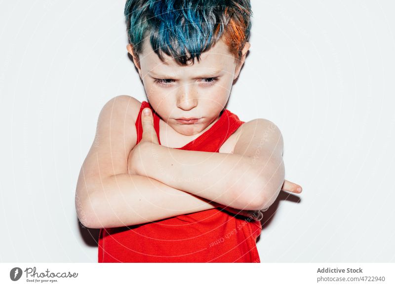 Beleidigter Junge mit gefärbtem Haar Kind unanständig schelmisch rebellisch Porträt ungehorsam widerspenstig verschränkte Arme beleidigt nachtragend ernst Raum