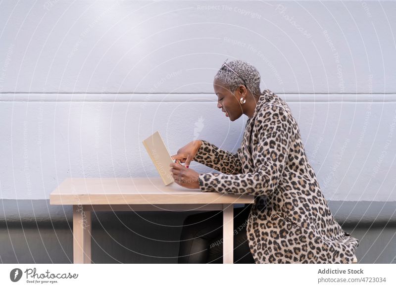 Schwarze Frau liest Brief aus dem Cafe lesen Café Terrasse Straße Stil Outfit Großstadt trendy Afroamerikaner schwarz Tisch Dame Zeitvertreib Kantine Bekleidung