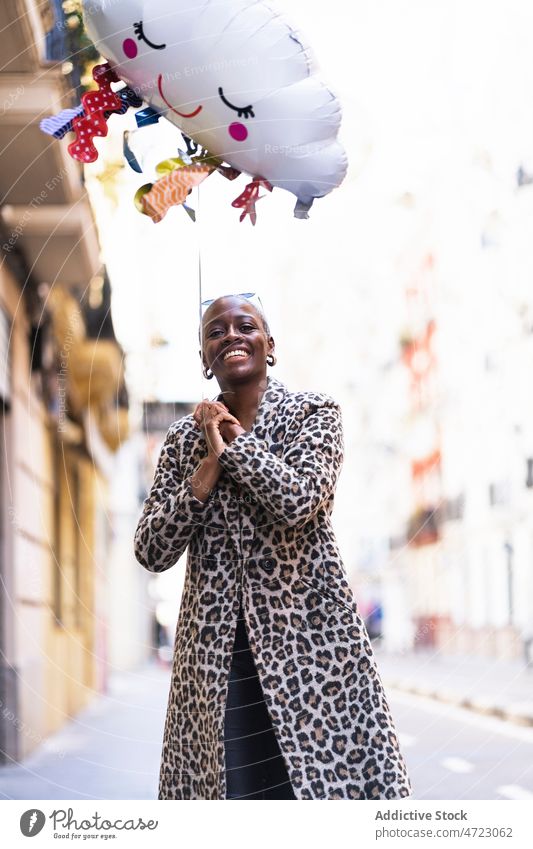 Fröhliche schwarze Frau mit Wolkenballon auf der Straße Luftballon Cloud regnet spielerisch Großstadt Stil sorgenfrei Vergnügen Zeitvertreib Vorschein