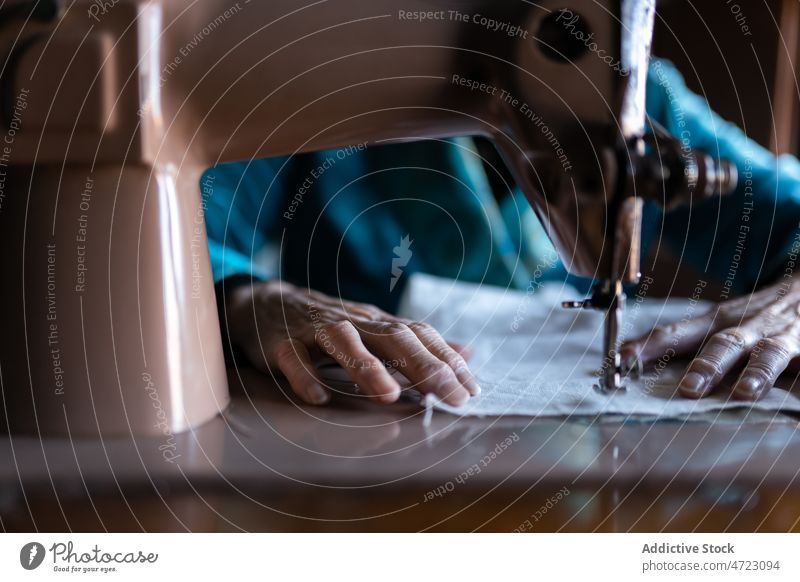 Unbekannte Frau näht an einer Maschine Nähmaschine Nähen Textil Näherin Basteln Hobby Vorrichtung Faser Instrument Stil Garn Design Raum Handwerkerin Tisch
