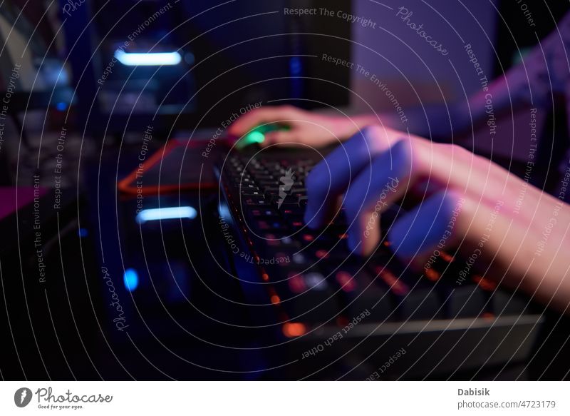 Gamer spielen ein Computerspiel, verwenden eine neonfarbene Tastatur Spiel Keyboard online Spieler cyber dunkel Sucht hintergrundbeleuchtet Spielen Licht RGB