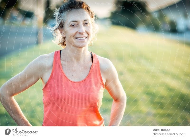 Echte junge reife kaukasische Frau in einer Sportkleidung im Park an einem sonnigen Nachmittag. Lifestyle Training Gesundheit Fitness Lächeln echte Menschen
