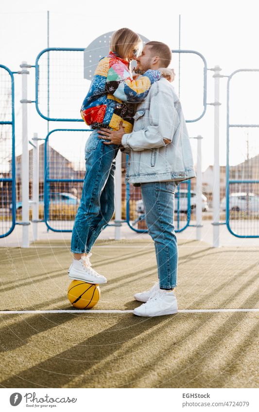 Paar berührt ihre Nasen auf einem Basketballplatz. Mädchen auf dem Basketballplatz. Glückliche Freundin und Freund Erwachsener Zuneigung anhänglich Ball Korb