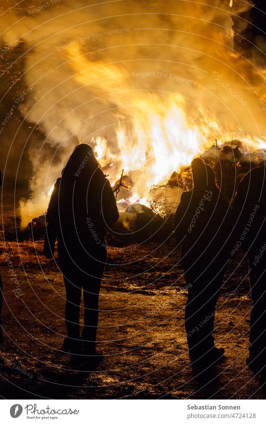 Silhouette von Menschen, die vor einem großen Feuer stehen Nacht Flamme orange Gefahr Licht gelb rot erwärmen Hintergrundbeleuchtung schwarz Rauch Europa Stehen