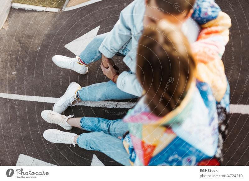 Draufsicht auf ein unerkanntes junges Paar, das zwischen den Schildern auf dem Boden eines Skateparks sitzt Sitzen unkenntlich Stock Skateplatz Freund Freundin