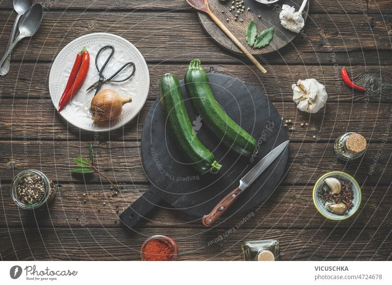 Lebensmittel Hintergrund mit Zucchini auf dunklen Schneidebrett mit Küchenmesser dunkel Messer Lebensmittelhintergrund zwei Küchenkräuter Gewürze