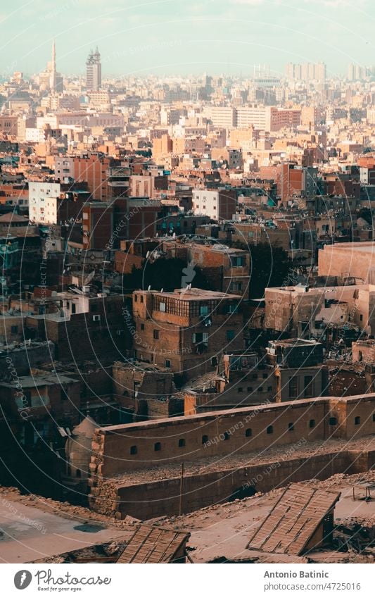 Blick auf zahlreiche Gebäude und Dächer von Kairo, der Millionenmetropole mit ihren kleinen Häusern und riesigen Wohnblocks. Orangefarbene Sandstimmung im Winter in Kairo