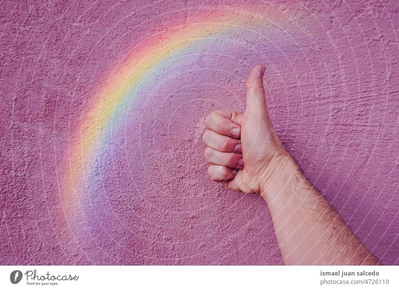 Daumen und Regenbogen auf der rosa Wand, lgbt Symbol Daumen hoch Hand LGBT-Symbol Farben farbenfroh schwuler Stolz Igbt-Flagge Vielfalt Toleranz aufgeschlossen