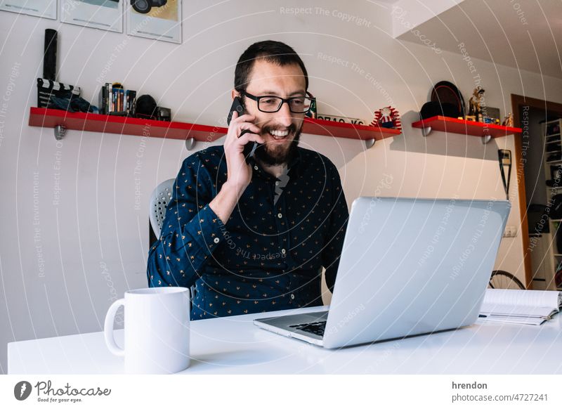 Junger Mann telefoniert in seinem Büro zu Hause Heimarbeitsplatz arbeiten junger Erwachsener Arbeiter Lebensstile Kleinunternehmen Geschäftsmann Laptop