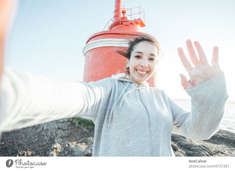 Junge arabische Frau, die ein Selfie auf der Küste Leuchtturm während einer Reise reisen, während lächelnd in die Kamera. Glückliche Erfahrungen, während Road Trip, neue Länder zu erkunden und Fotos für die Familie zu nehmen