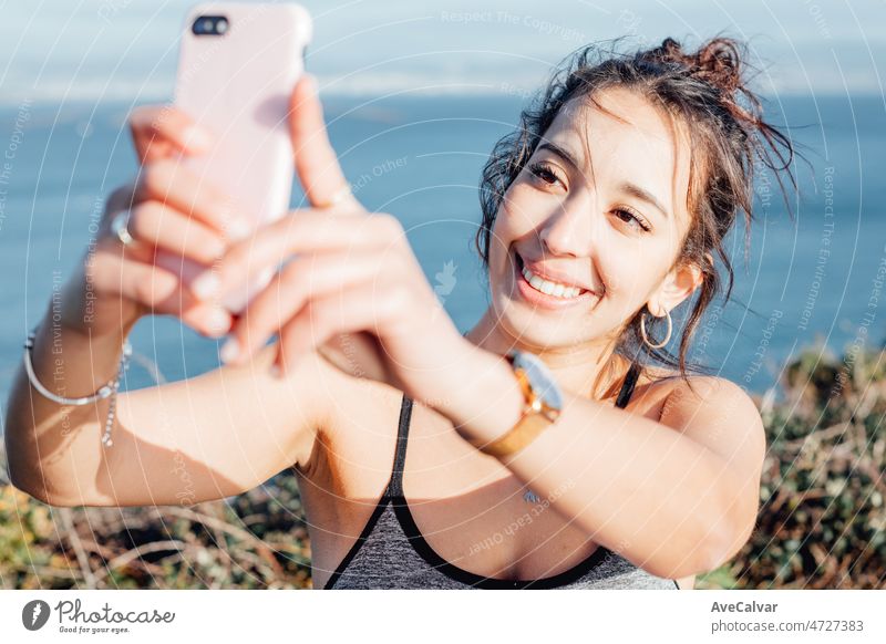 Junge Frau im Freien auf Sport Kleidung, die ein Selfie für soziale Netzwerk nach dem Training. Sorglos, positiv und Freiheit Konzept. Gesunder Lebensstil beim Sport im Freien. Glückliche Haltung
