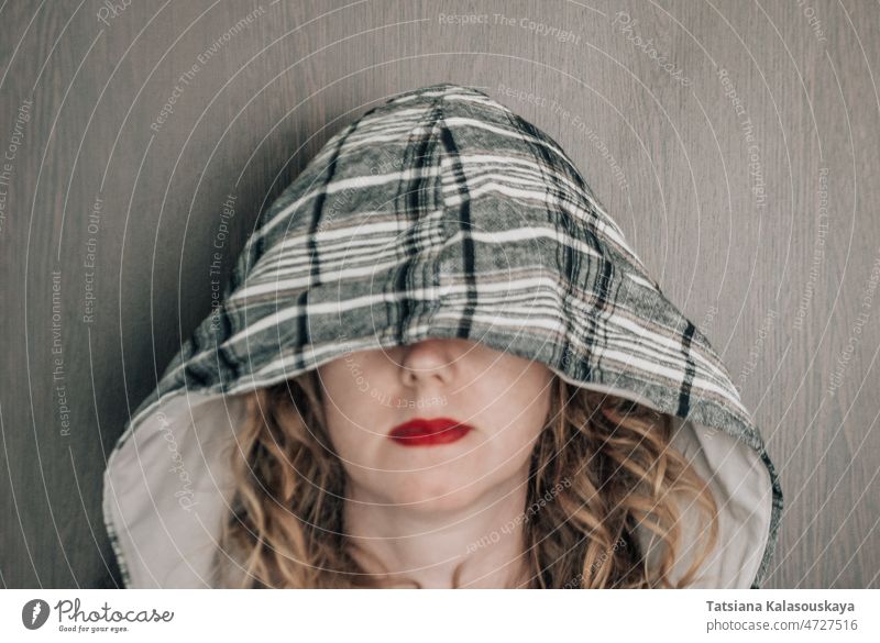 Lockige Frau mit einer Kapuze auf dem Kopf, die ihre Augen verdeckt horizontal Fotografie Kapuze - Kleidung Porträt eine Person Vorderansicht