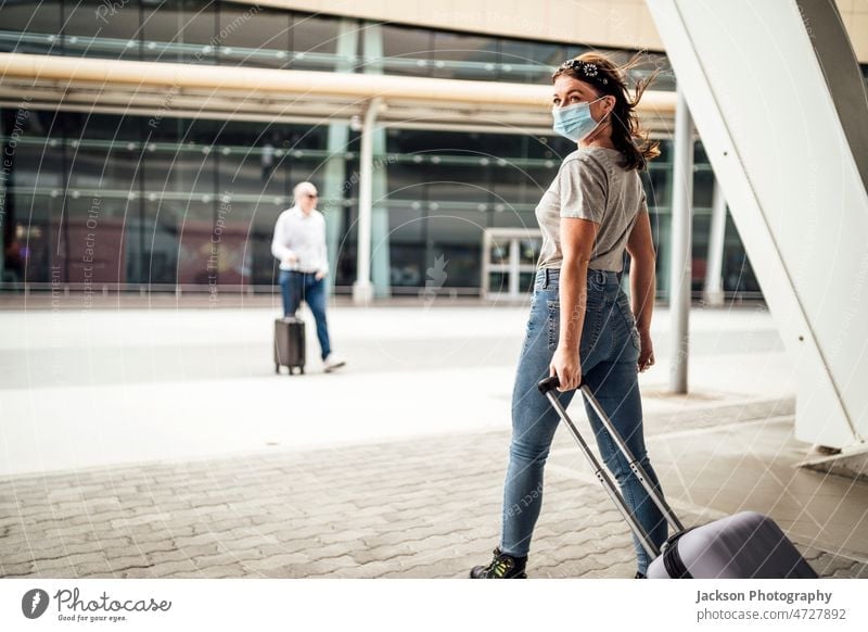 Eine junge Frau mit Maske geht mit dem Koffer zum Flughafen Reisender Gepäck reisen COVID Pandemie Mundschutz ankommen Technik & Technologie Coronavirus Pendler