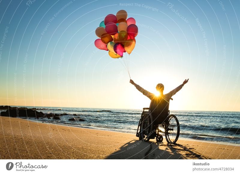 Alles ist möglich Frau Rollstuhl Glück Strand Ballons Sonnenuntergang Behinderte Hände nach oben feiern Fröhlichkeit Waffen Gesundheitswesen Freude Freizeit