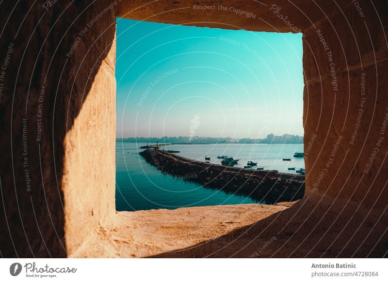 Die Bucht von Alexandria in Ägypten, gesehen aus einem Fenster der nahe gelegenen Zitadelle. Kalter Morgen an einem Wintertag, ein steinerner Hafenbogen erstreckt sich in die Ferne