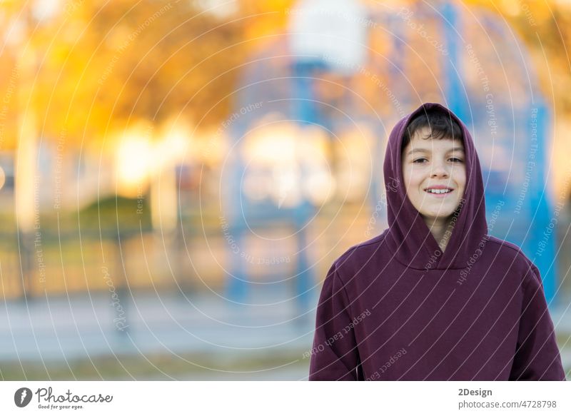 Lächelnder Teenager im Alter von 14-16 Jahren mit Kapuzenpulli im Freien. Schaut in die Kamera. Teenager mit Kapuze. Person Junge männlich Gesicht Porträt jung