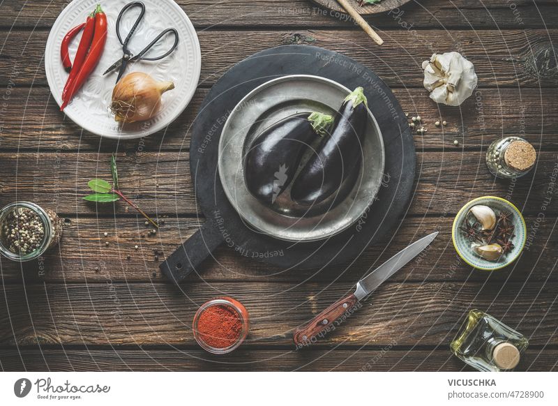 Lebensmittel Hintergrund mit zwei Auberginen auf dunklen Schneidebrett auf rustikalen Holztisch Küche Lebensmittelhintergrund dunkel hölzern Tisch Gewürze