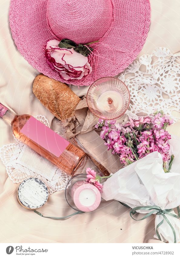 Rosa farbigen Picknick-Konzept mit Sonnenhut, Rose Weinflasche, Kerzen, Blumen, Baguette Rosenwein Flasche Käse rosa beige Decke romantisch Sommer Idee