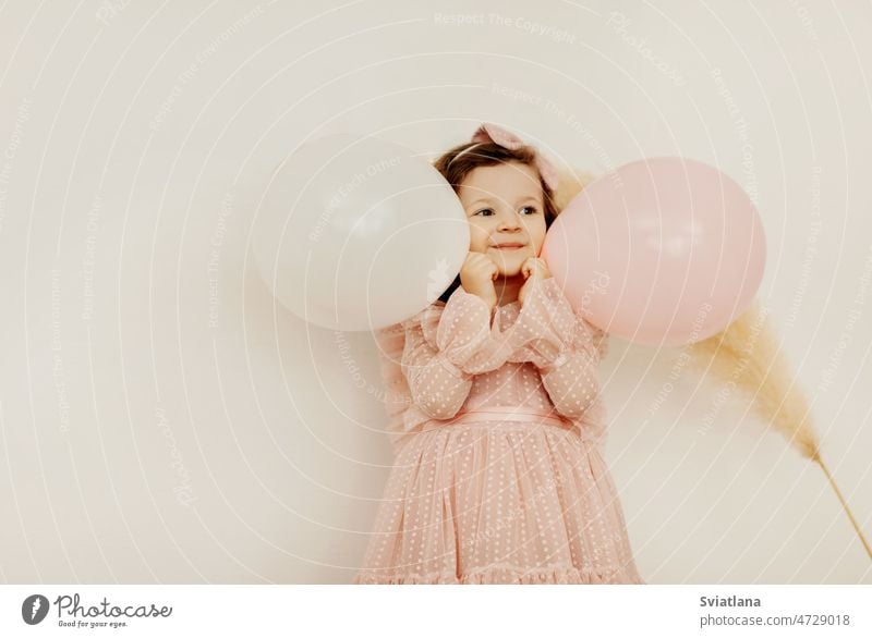 Ein charmantes kleines Mädchen mit Luftballons an ihrem Geburtstag hat Spaß und lacht Baby Kleid Bälle niedlich wenig Lächeln rosa schön Glück süß Lachen Licht