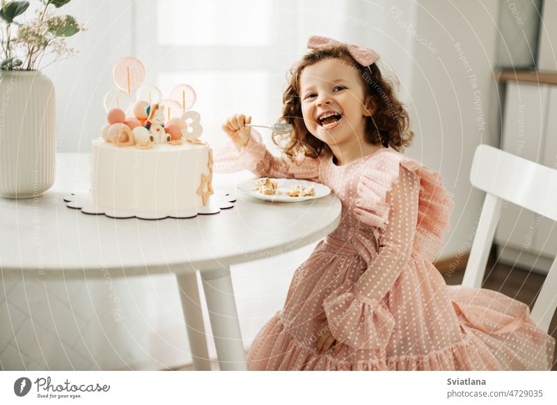 Ein lachendes kleines Mädchen isst an seinem Geburtstag zu Hause einen Geburtstagskuchen Kuchen Kind wenig hübsch essen heimwärts Glück Spaß süß Lebensmittel