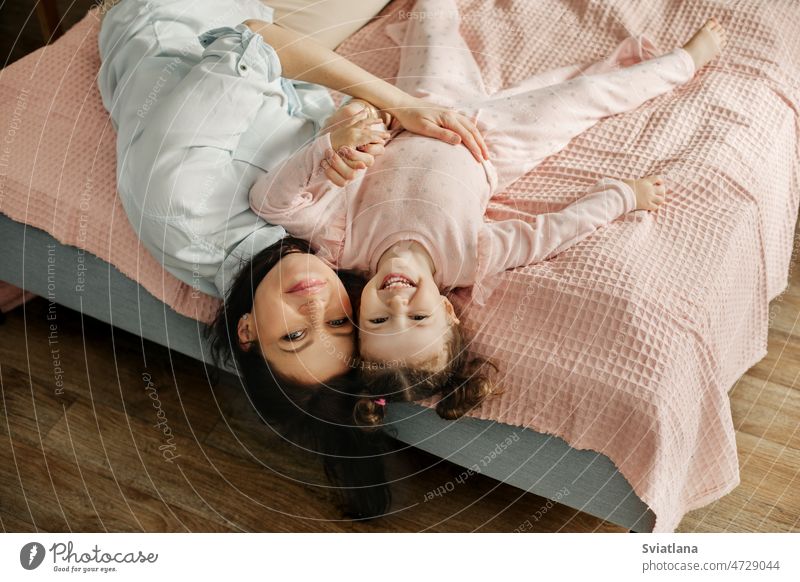 Mutter und Tochter liegen auf dem Bett und lächeln. Mama und Baby haben Spaß auf dem Bett. Glückliche, liebevolle Familie Spielen jung Mädchen Kind Schlafzimmer