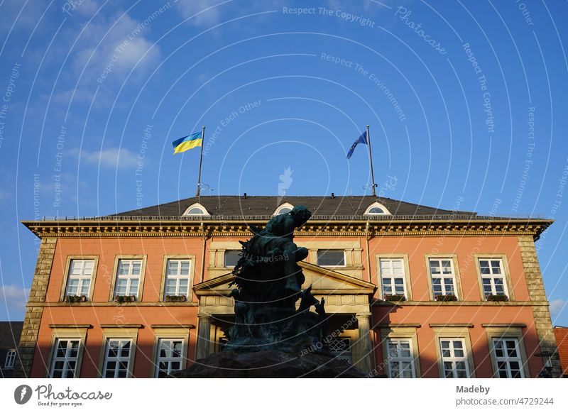 Die Fahne der Ukraine vor blauem Himmel im Sonnenschein auf dem Rathaus von Detmold am Marktplatz mit dem Donopbrunnen in Ostwestfalen-Lippe Flagge freiheit