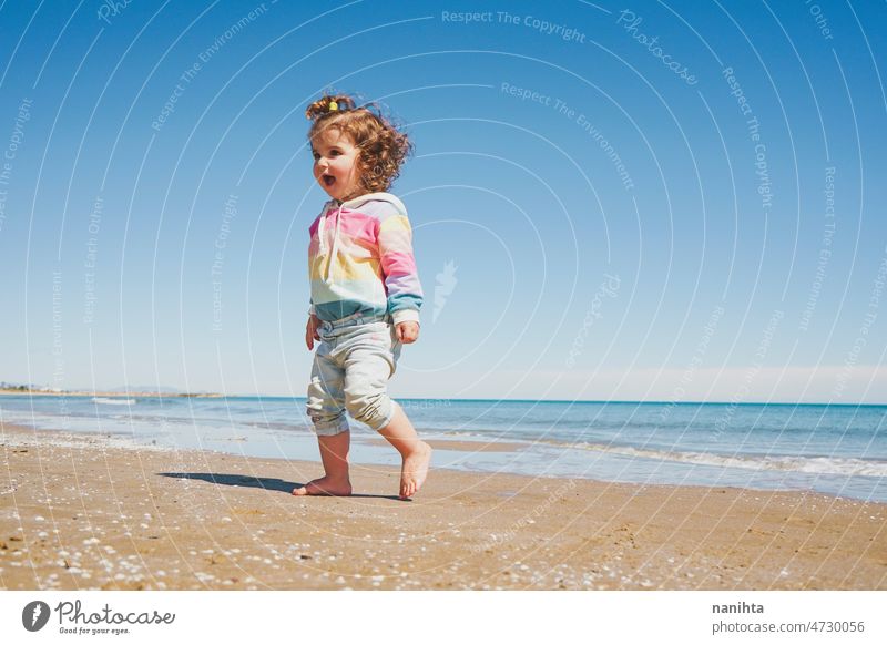 Großansicht eines kleinen Mädchens mit Regenbogen-Kapuzenpulli beim Spielen am Strand Freiheit Fröhlichkeit Feiertage Baby Kleinkind Familie frei MEER Ufer