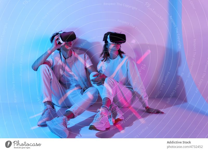 Paar in VR-Headset sitzt an der Wand Virtuelle Realität Cyberspace Zukunft Augmented Reality interaktiv Technik & Technologie erkunden Schutzbrille futuristisch