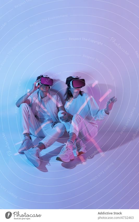 Paar in VR-Headset sitzt an der Wand Virtuelle Realität Cyberspace Zukunft Augmented Reality interaktiv Technik & Technologie erkunden Schutzbrille futuristisch