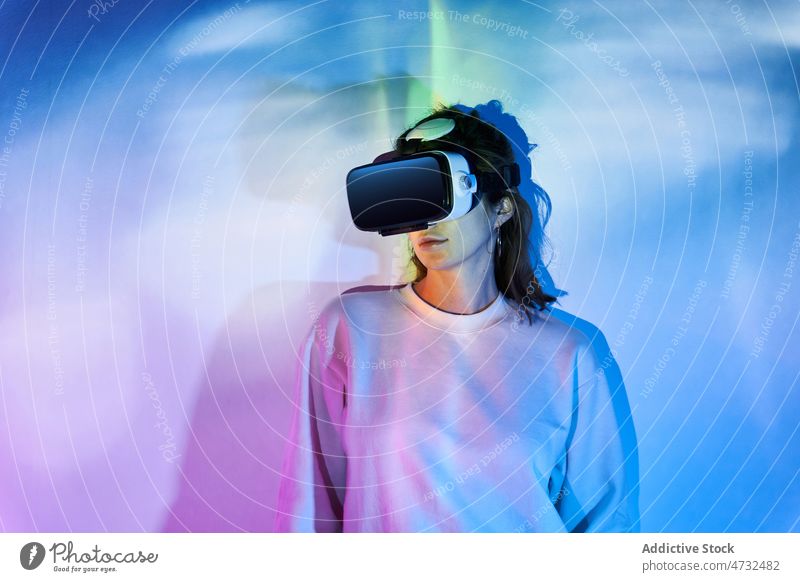 Frau mit VR-Headset in der Nähe einer Wand mit leuchtenden Lichtern Virtuelle Realität Cyberspace Zukunft Augmented Reality interaktiv erkunden