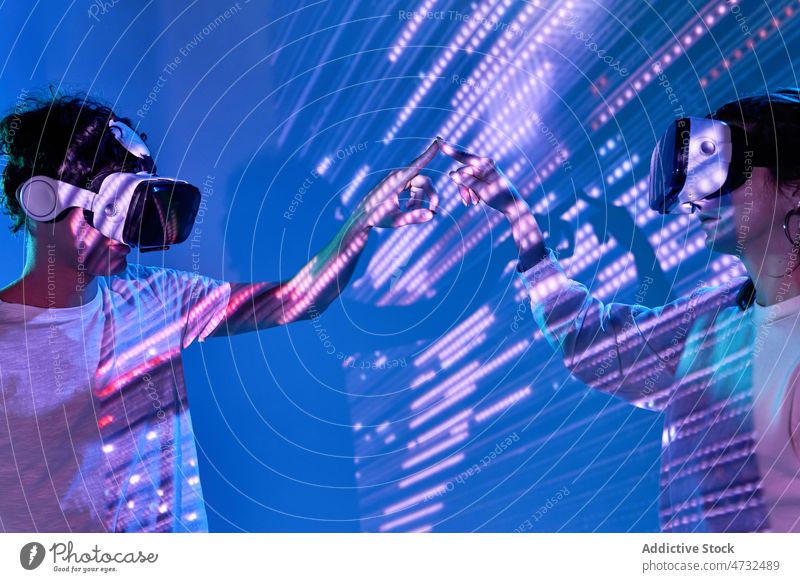 Pärchen erkundet den Cyberspace unter glühenden Lichtern Paar VR Virtuelle Realität Headset Zukunft Metaversum interaktiv Technik & Technologie erkunden