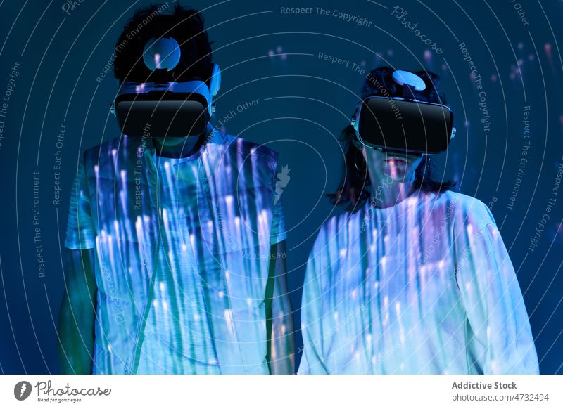Paar mit VR-Headset im dunklen Studio Virtuelle Realität Cyberspace Zukunft Augmented Reality interaktiv Technik & Technologie Licht erkunden Schutzbrille