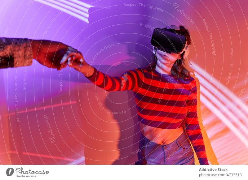 Frau in VR-Headset hält Hände mit gesichtslosem Partner Virtuelle Realität Cyberspace Metaversum Zukunft Händchenhalten interaktiv Technik & Technologie