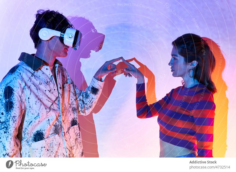 Frau berührt den Finger eines Mannes im VR-Headset Paar Virtuelle Realität Cyberspace Zukunft Metaversum interaktiv Technik & Technologie erkunden Schutzbrille