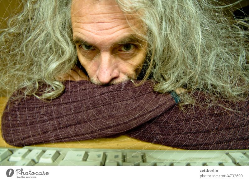 Alter Hippie am Computer Mann alt rentner althippie ortrait Gesicht Kontakt blickkontakt Auge nase Arme verschränkt tastatur computertatatur zweifelhaft warten