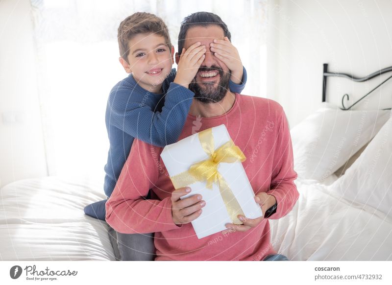 Sohn schließt seinem Vater die Augen und überreicht ein Geschenk Zuneigung Vollbart Geburtstag Kasten Junge Kaukasier feiern zu feiern heiter Kind Kindheit