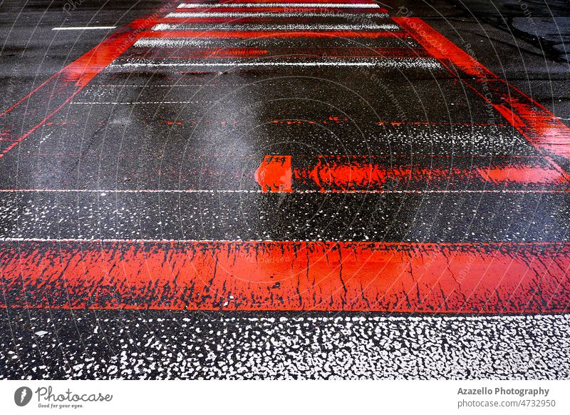 Nasse Asphaltstraße mit roten und weißen Zebrastreifen. abstrakt Kunst Hintergrund hell Nahaufnahme durchkreuzen Überfahrt Design Laufwerk Fahrweg verblassen