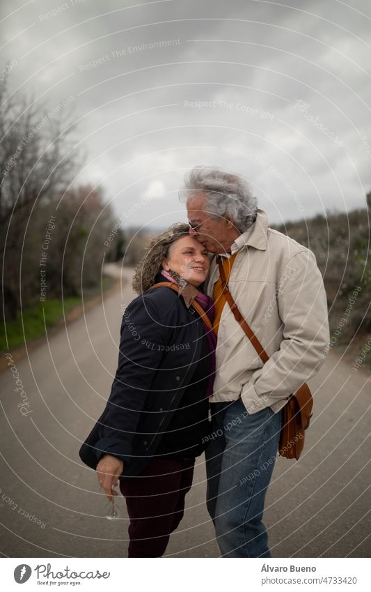 Ein Paar, Mann und Frau, 60 und 70 Jahre alt, mit grauen Haaren, zeigen ihre Zuneigung mit einem Kuss während eines romantischen Frühlingsspaziergangs in einer ländlichen Gegend in der Provinz Zaragoza, Aragon, Spanien