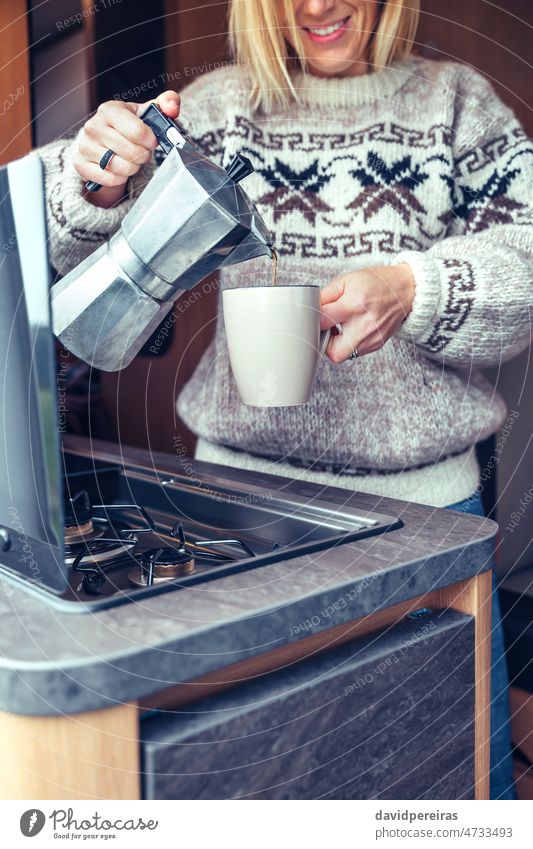 Frau serviert Kaffee mit Kaffeemaschine im Wohnmobil unkenntlich Servieren italienische Kaffeemaschine Lächeln Tasse Wollpullover Detailaufnahme