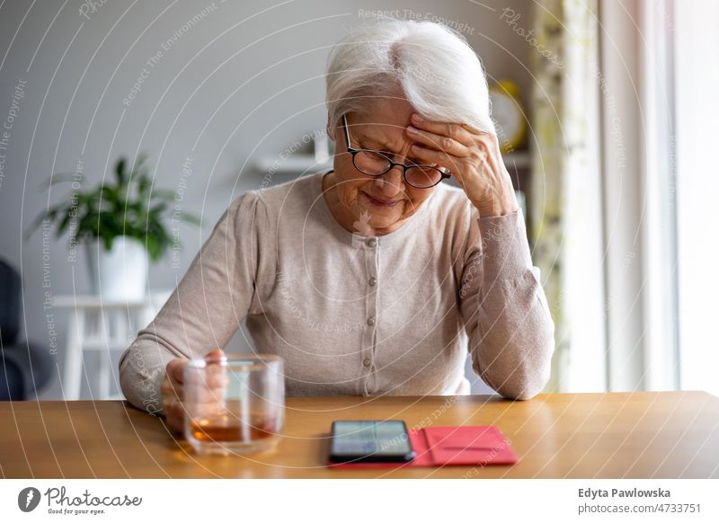 Ältere Frau benutzt Mobiltelefon zu Hause Brille allein häusliches Leben älter Oma Großmutter graue Haare heimwärts im Innenbereich Lifestyle reif alt