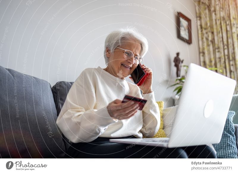 Ältere Frau beim Online-Shopping am Laptop zu Hause Brille allein häusliches Leben älter Oma Großmutter graue Haare heimwärts im Innenbereich Lifestyle reif alt