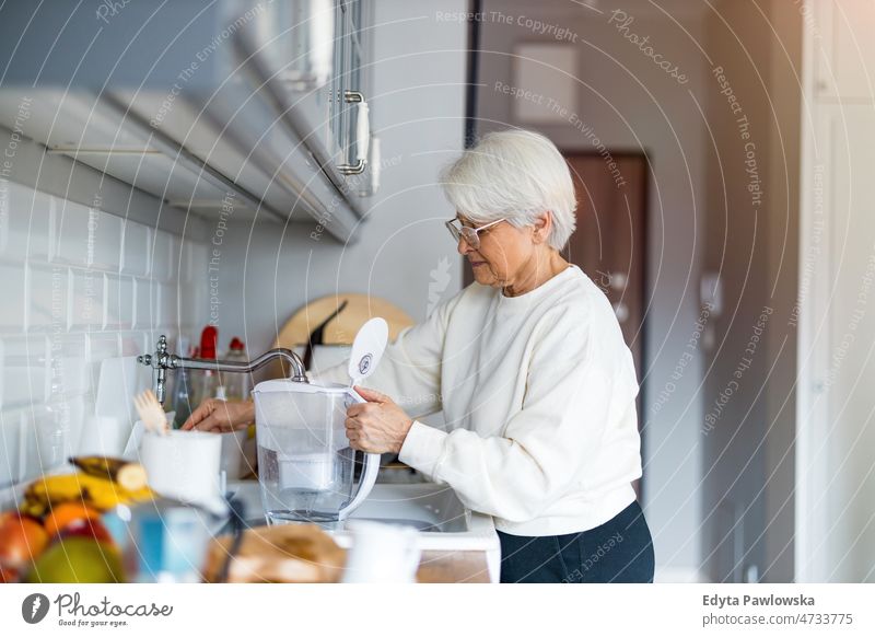 Aufnahme einer älteren Frau in ihrer Küche allein zu Hause häusliches Leben Oma Großmutter graue Haare heimwärts im Innenbereich Lifestyle reif alt eine Person