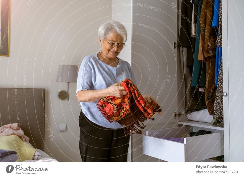 Ältere Frau, die ihre Garderobe auf Vordermann bringt allein zu Hause häusliches Leben älter Oma Großmutter graue Haare heimwärts im Innenbereich Lifestyle reif
